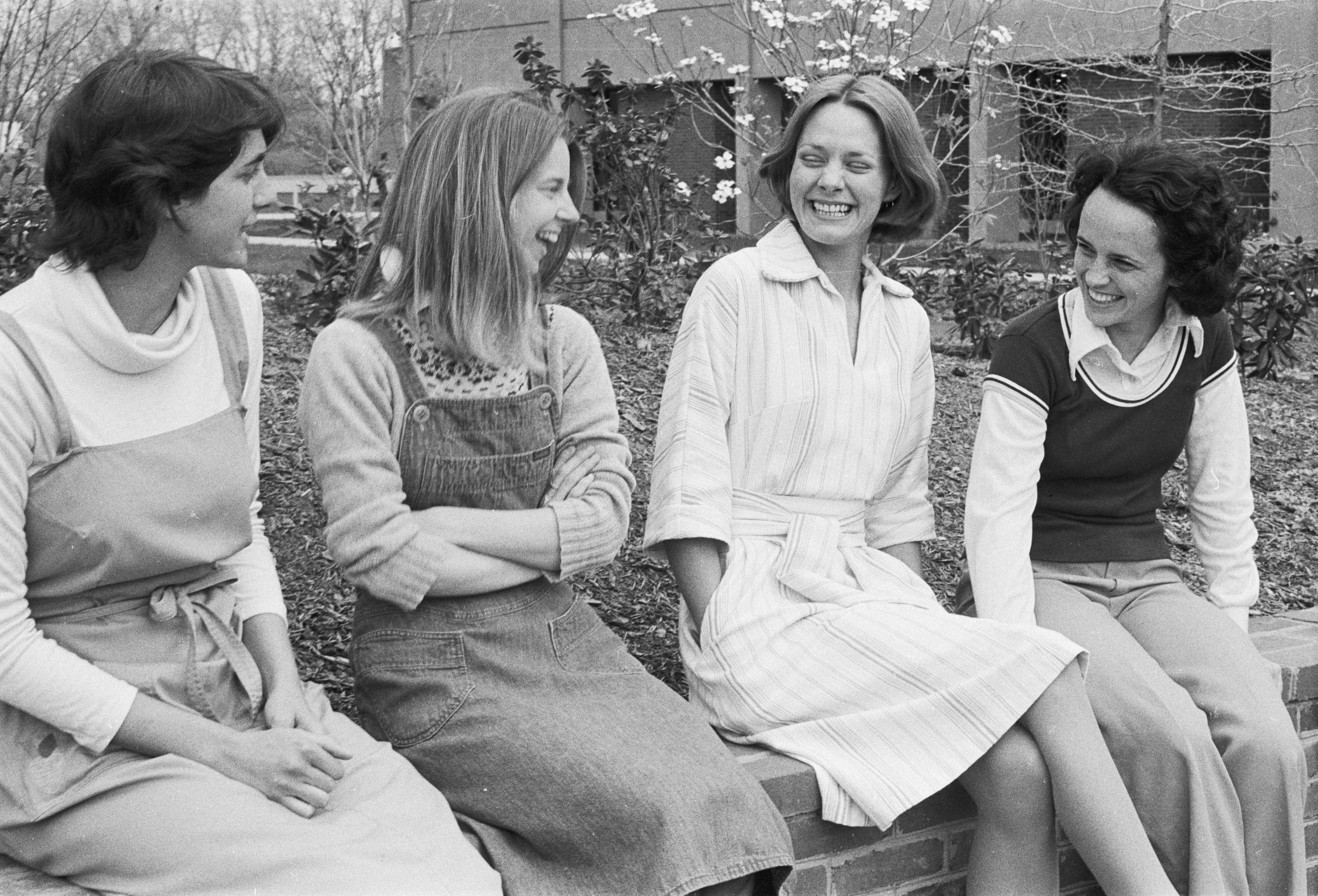 Black and white photograph of four women smiling outside