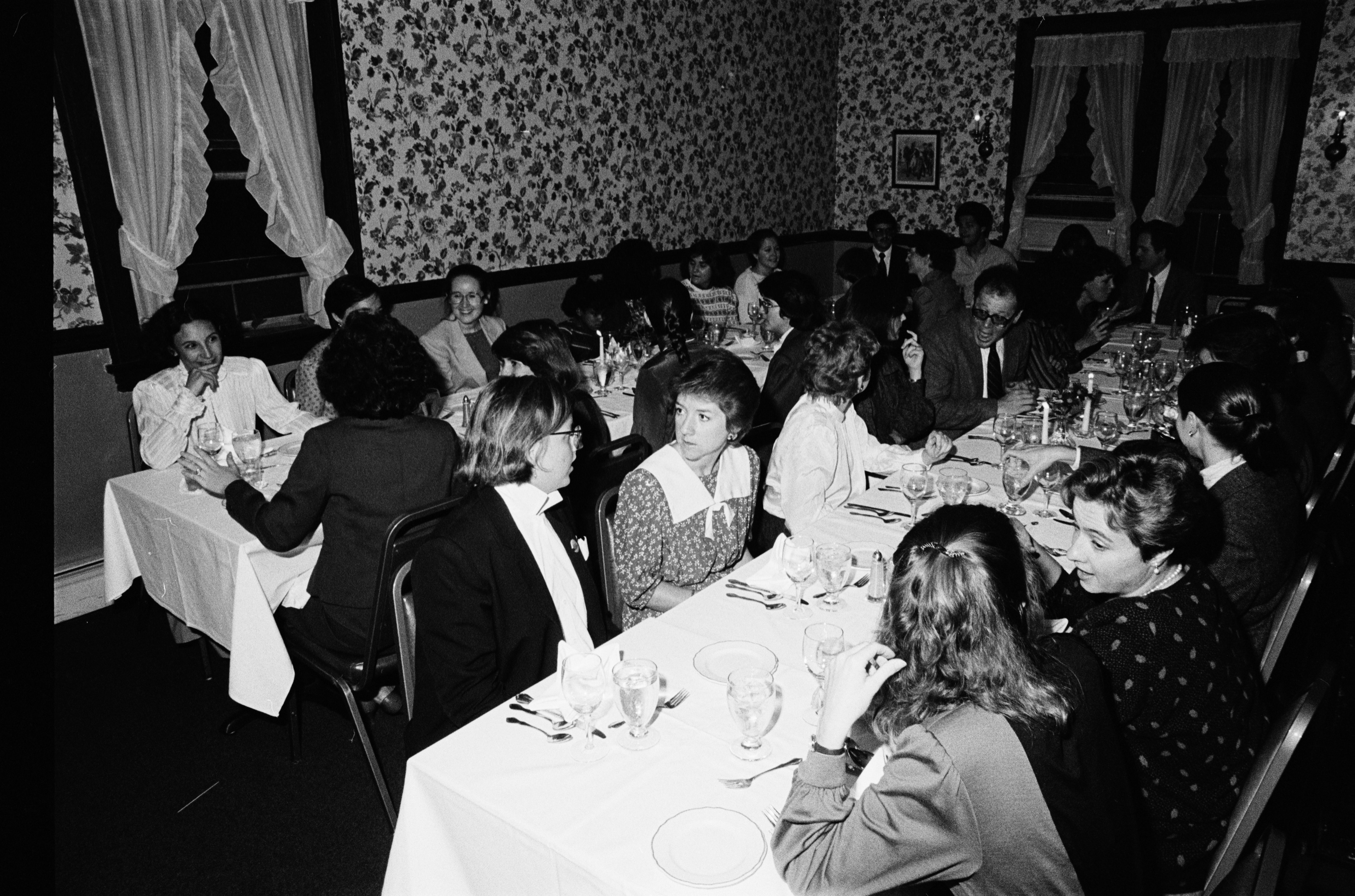 Black and white photograph of men and women in a banquet hall
