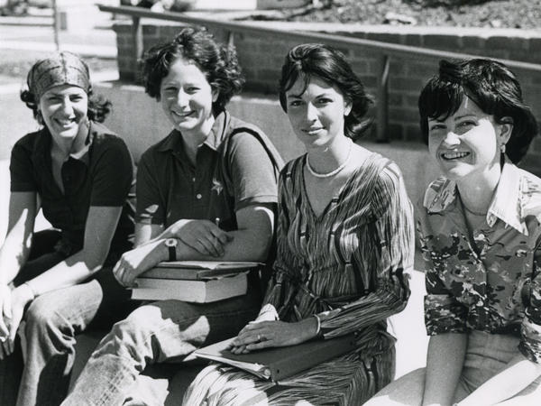 Black and white photograph of four women smiling outside