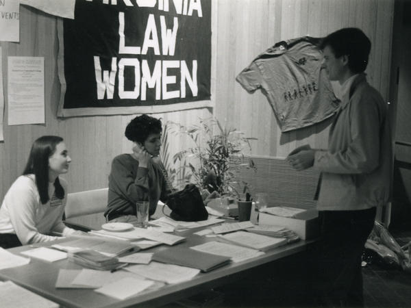 Black and white photograph of two women tabling in front of Virginia Law Women banner