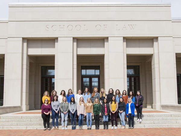Color photograph of a group of smiling women in front of the Law School