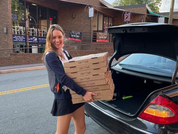 Color photograph of a woman carrying pizza boxes