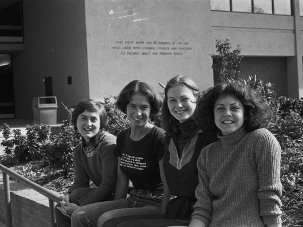 Black and white photograph of four women smiling outside