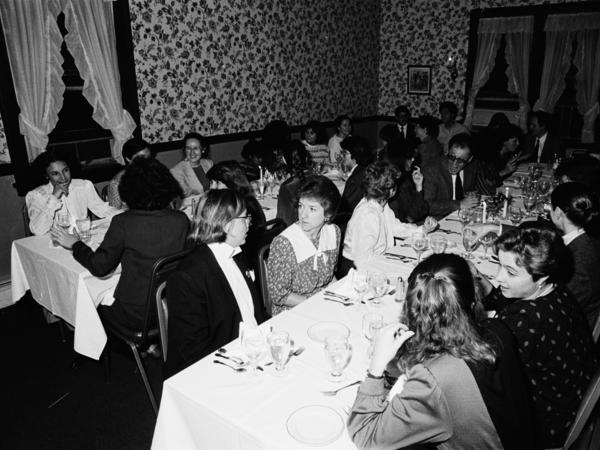 Black and white photograph of men and women in a banquet hall