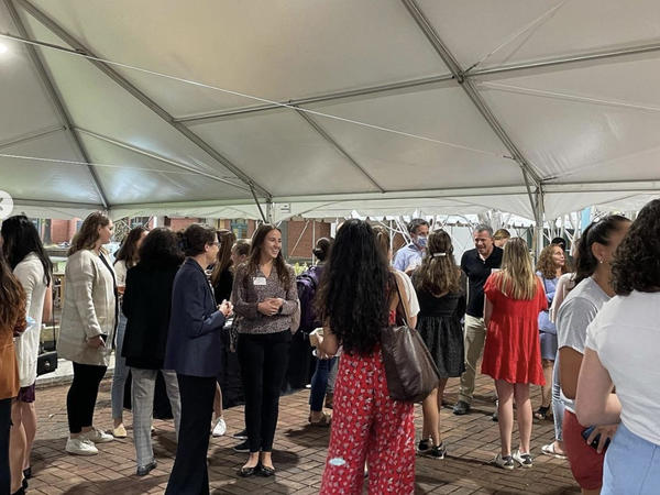 Color photograph of people mingling under a tent